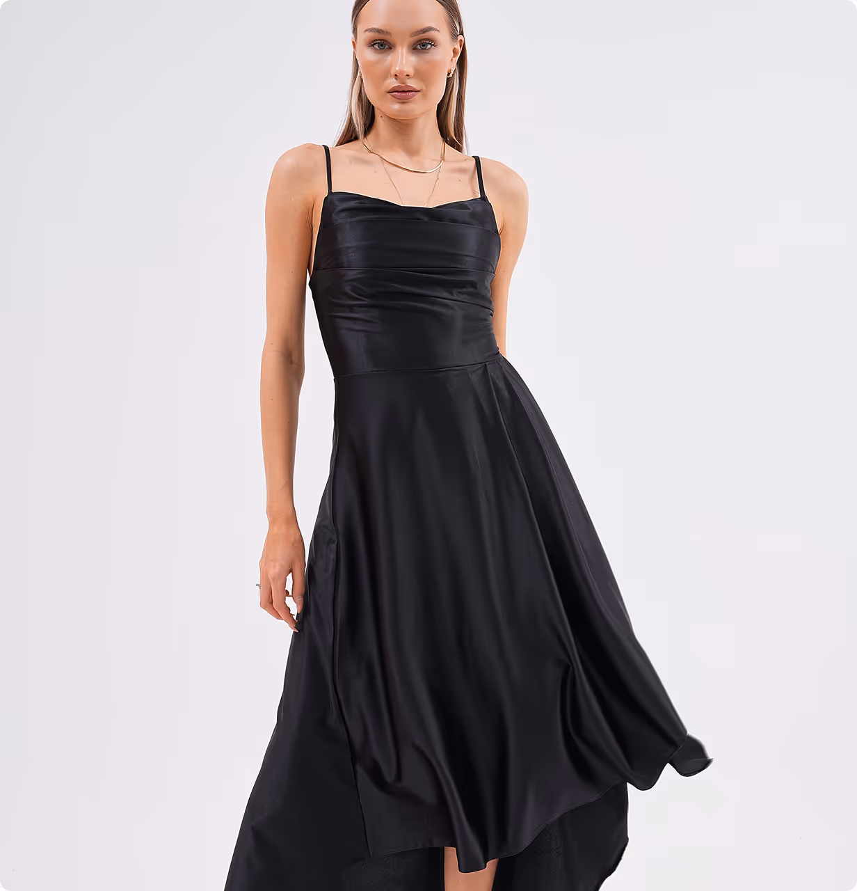 Model in Celestera black satin gown with asymmetrical hemline, posing front-facing with relaxed hands.