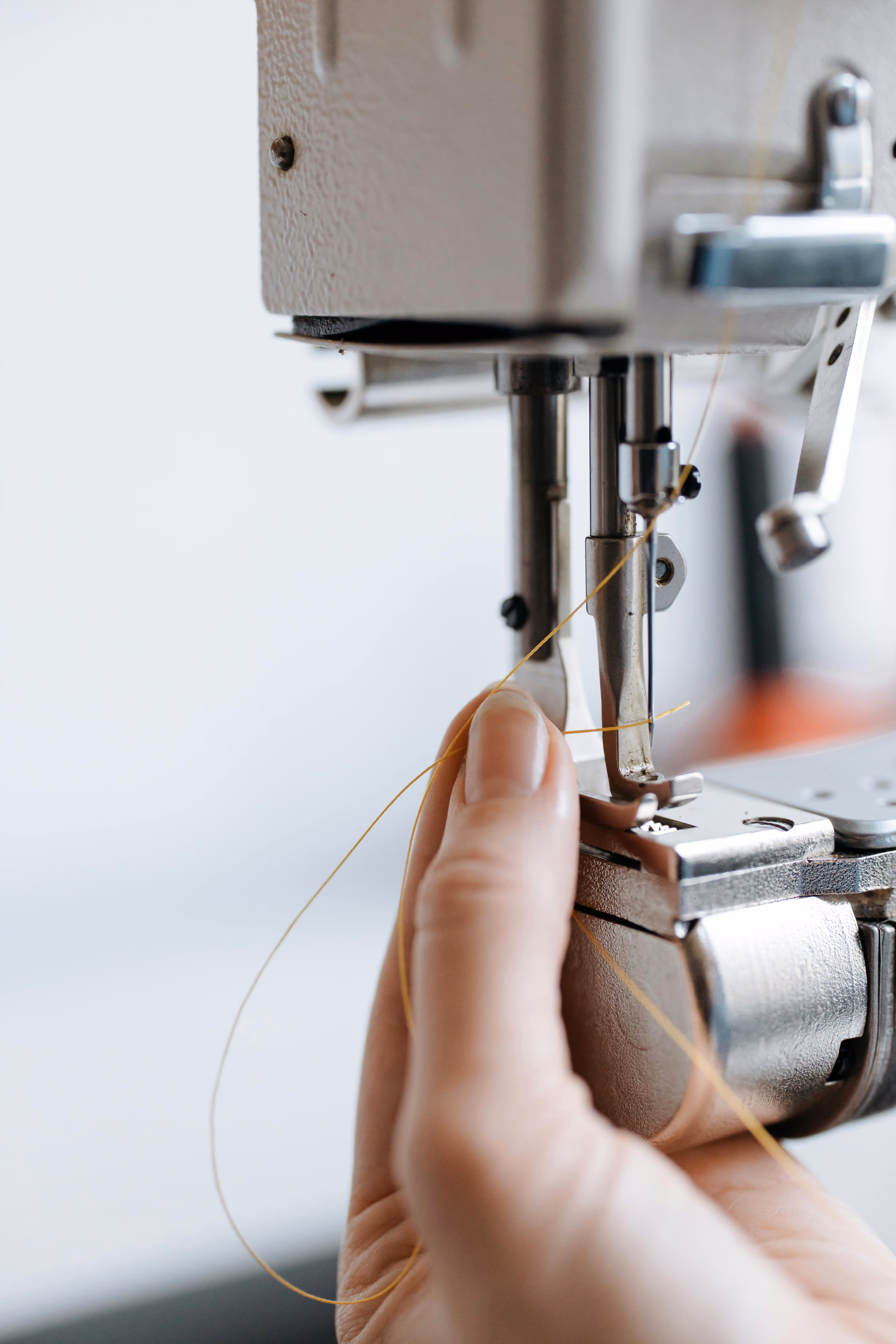 Close-up of a tailor’s hand sewing fabric on an industrial machine – Farika craftsmanship