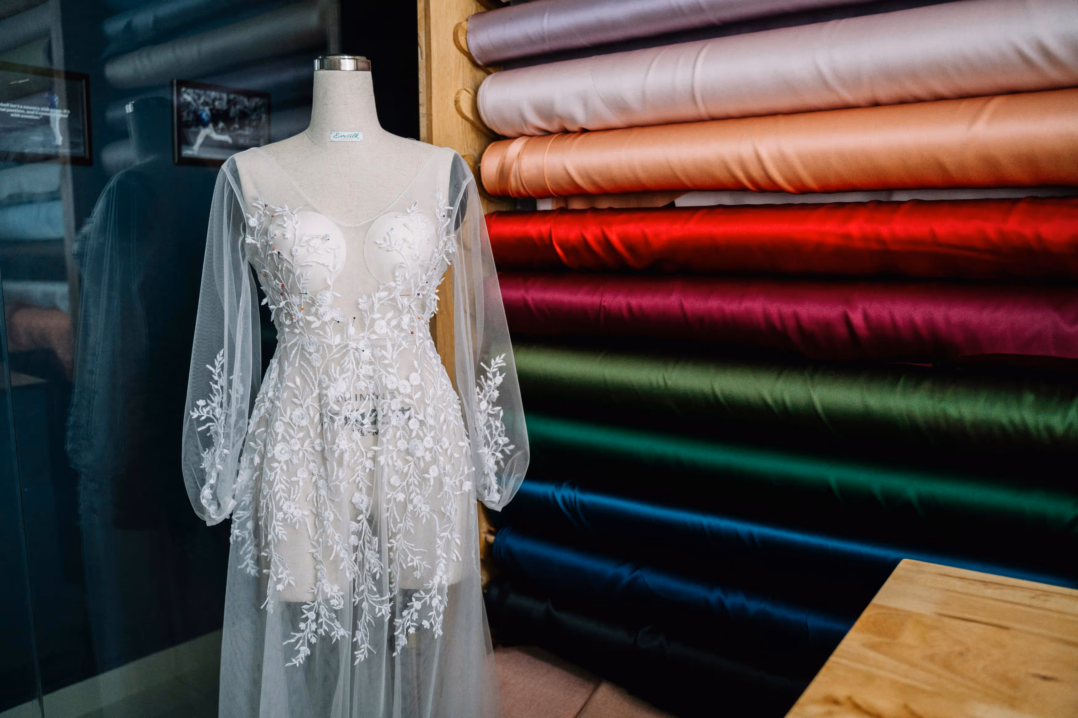 White tulle gown displayed in front of colorful fabric rolls – Farika Style Trends