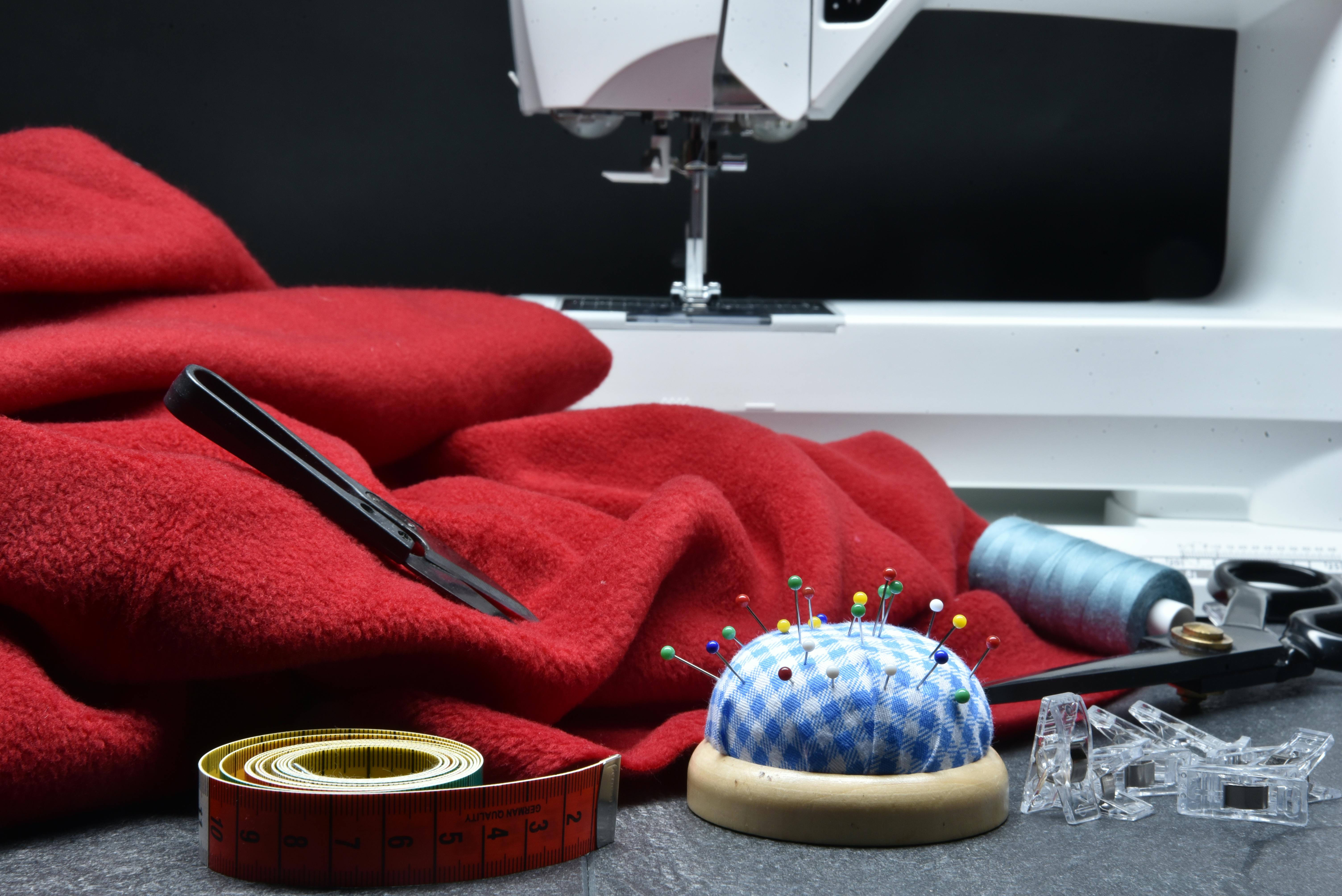Tailoring setup with red fabric, sewing machine, and tools representing Farika’s craftsmanship and design process.