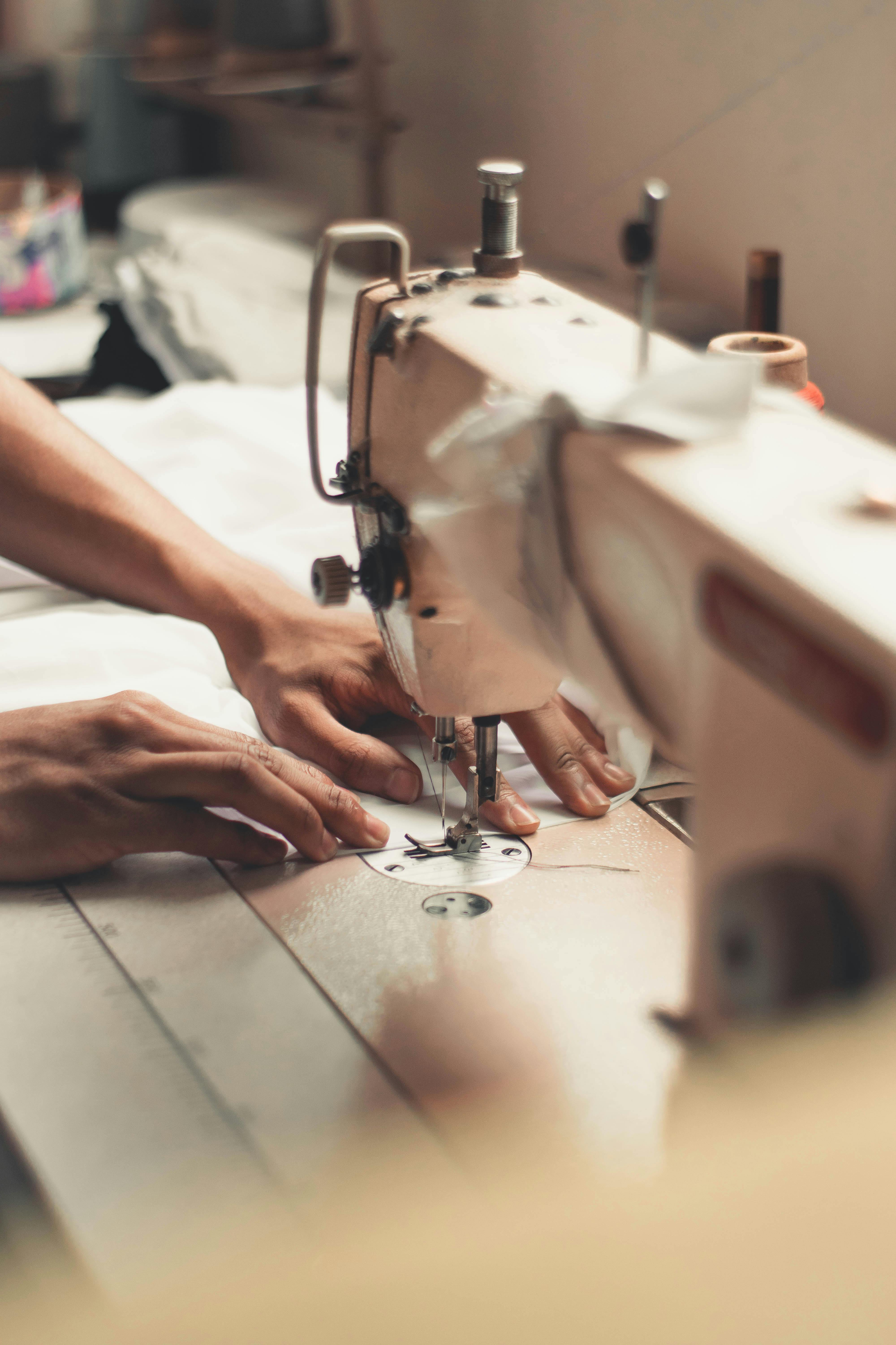 Close-up of hands guiding fabric through an industrial sewing machine – showcasing precision tailoring at Farika