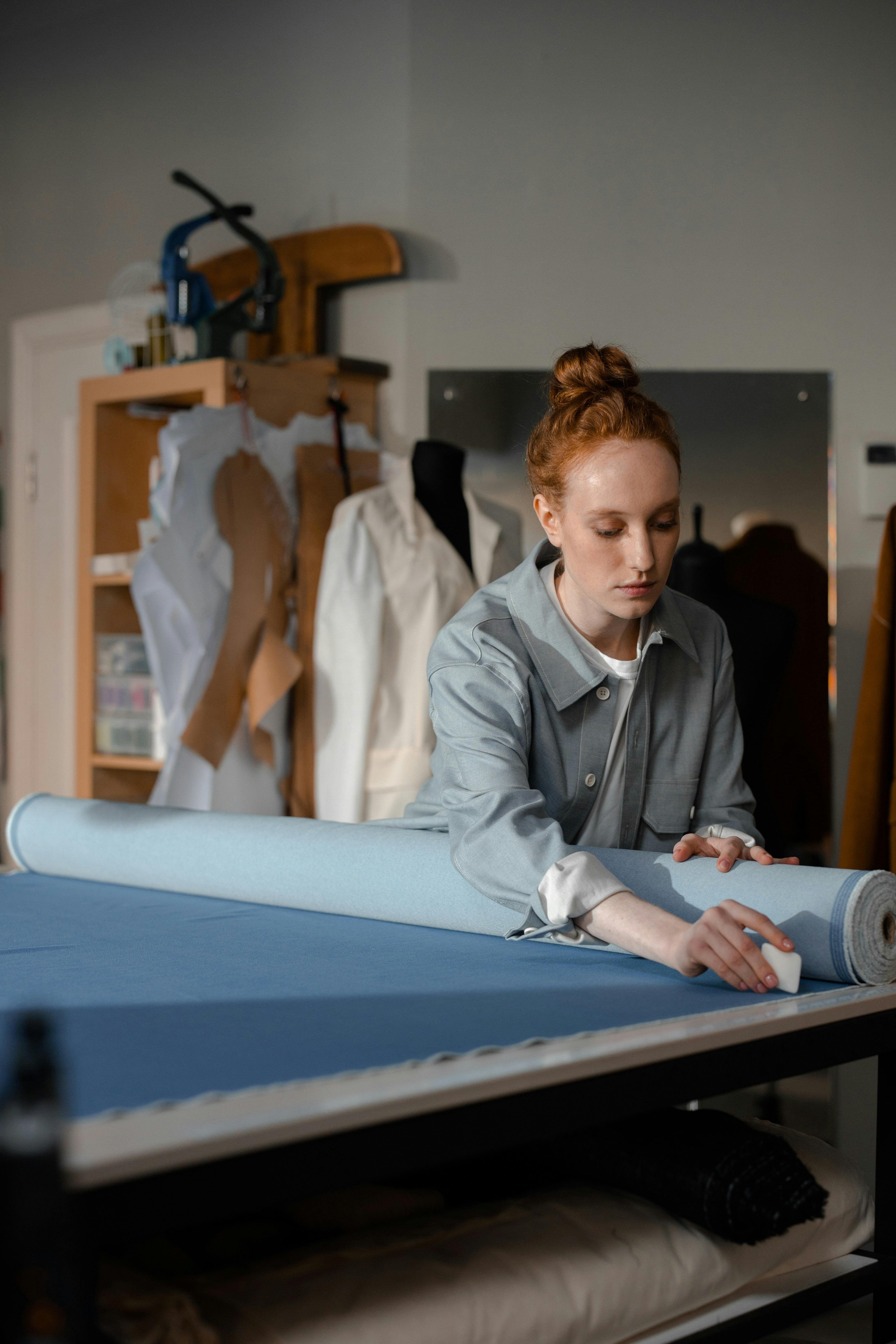 Young female artisan measuring and preparing fabric on a tailoring table at Farika atelier