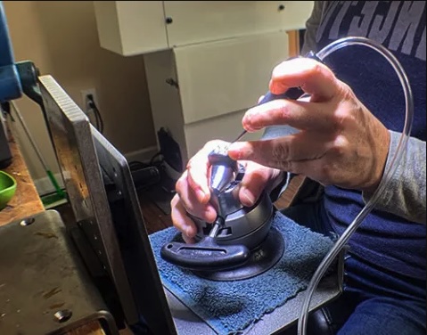 Jeweler using a hand engraving tool to work on a ring held in a ball vise