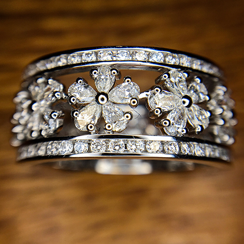 White gold floral diamond ring featuring rows of round and pear-shaped stones arranged in daisy motifs