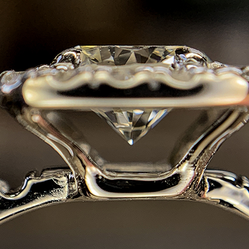 Close-up side view of a diamond engagement ring showing the pavilion of the center stone and intricate setting details