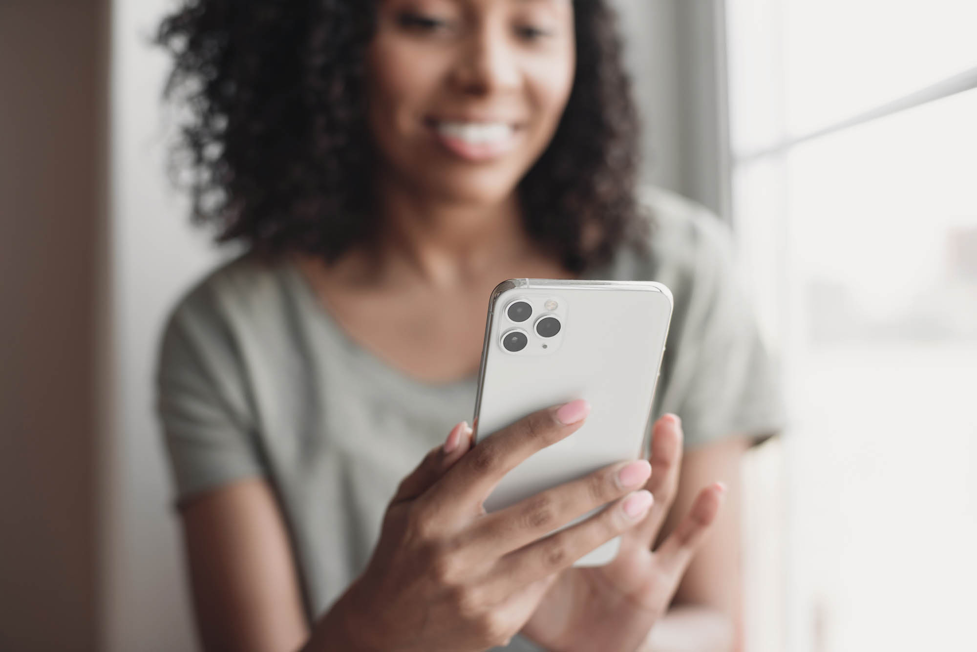 A young woman sitting on the floor with her phone ordering bras after using Fit:match to find her correct fit.