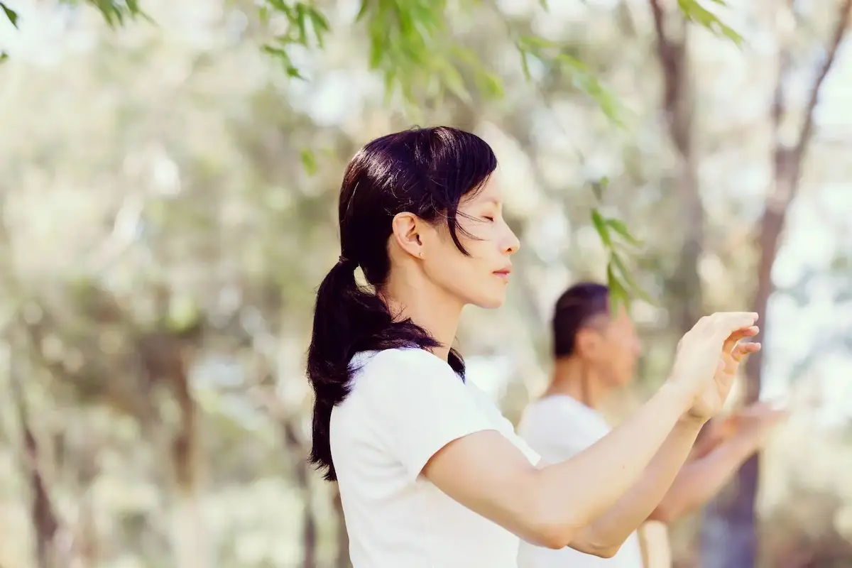 Femme pratiquant le Qi Gong dans la nature - Cours en ligne
