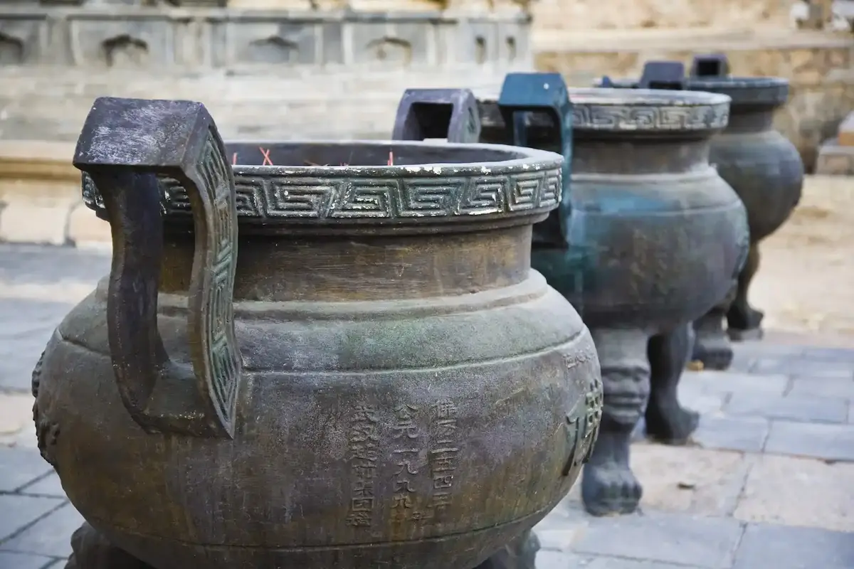 3 tripodes en bronze devant un temple