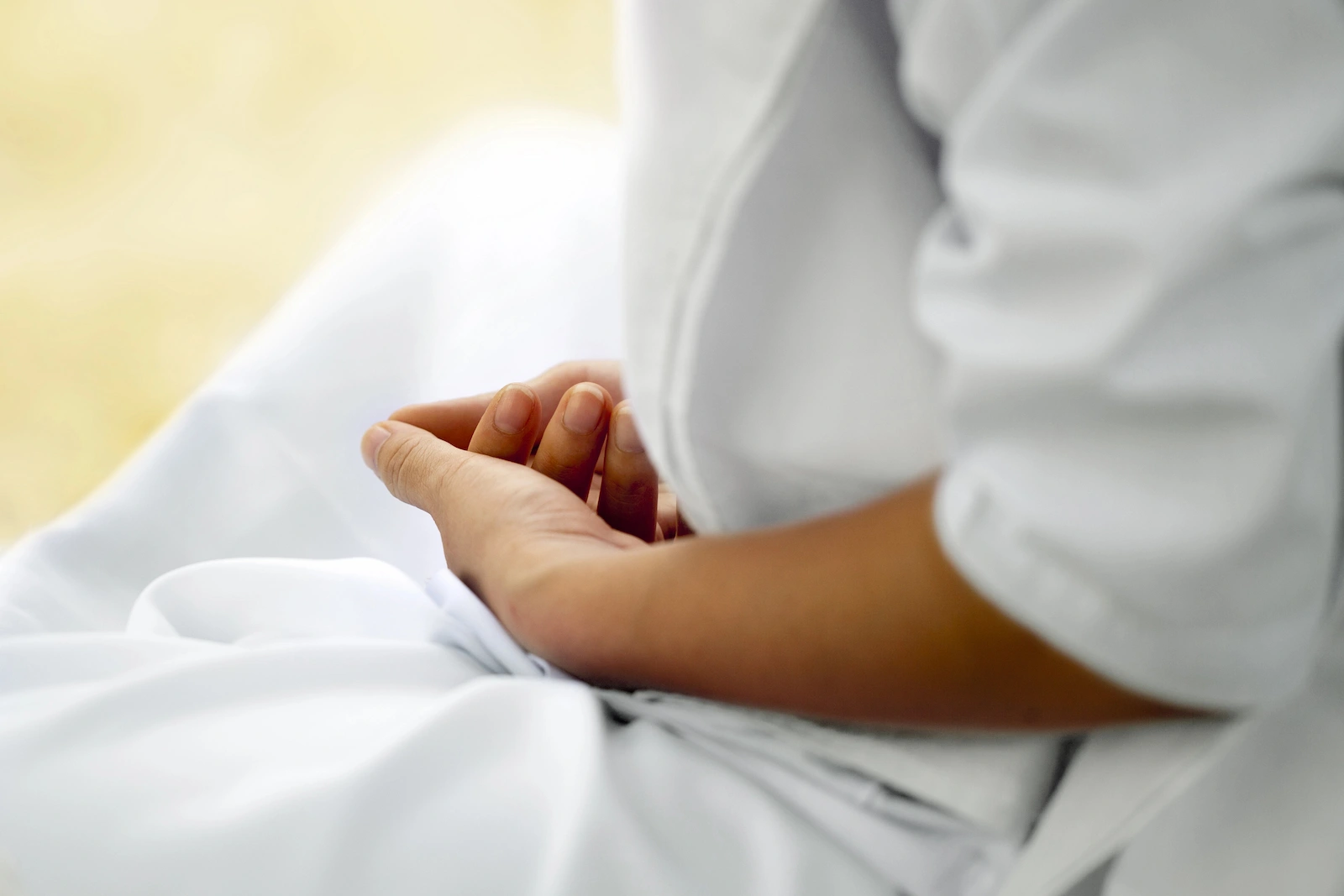 Une personne médite assise sur le sol avec les mains devant le ventre