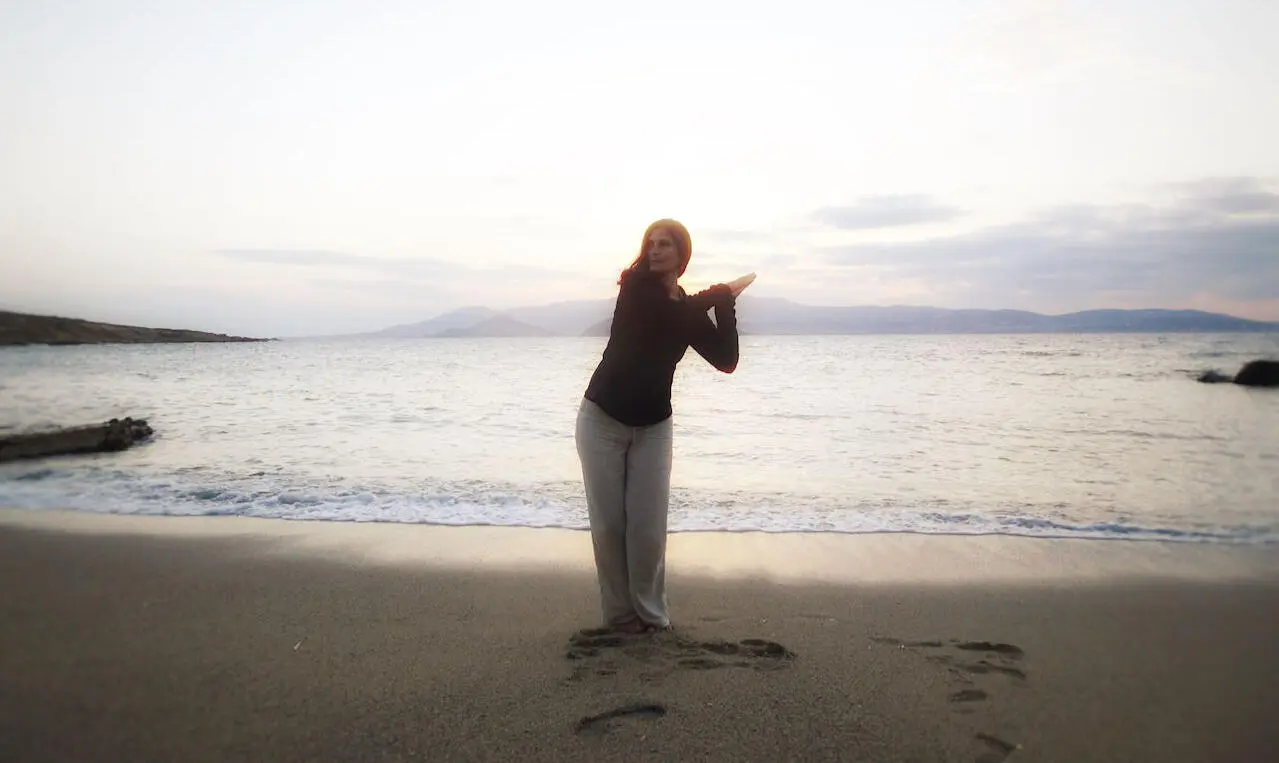 Maëlla Caro qui pratique le Qi Gong au bord d'une plage à la tombée de la nuit.