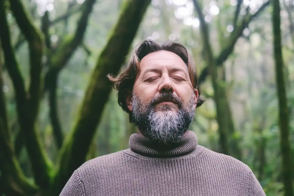 Un homme au visage serein pratique le qi gong dans la nature
