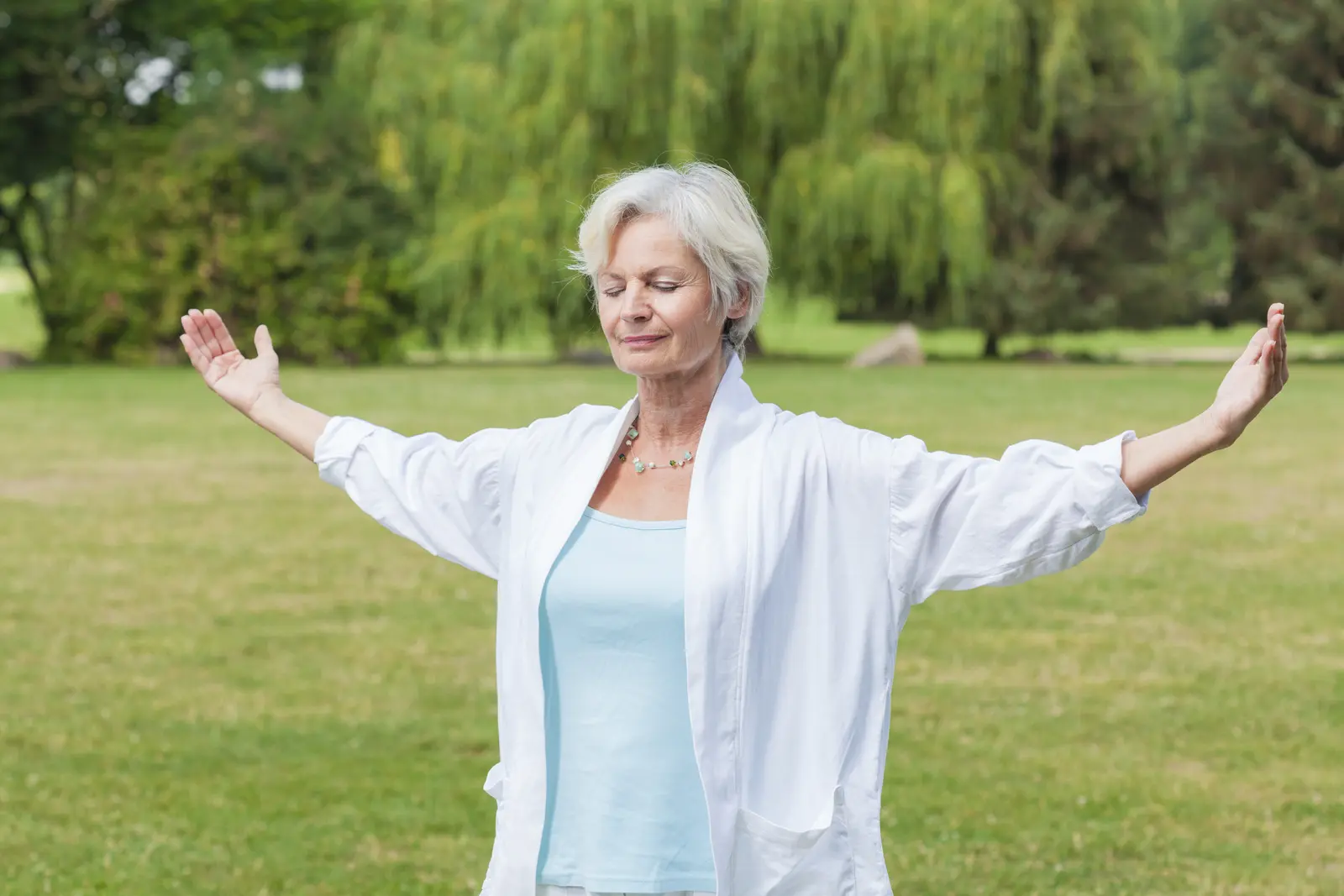 Une femme avec les bras grands ouverts pratiquant le qi gong
