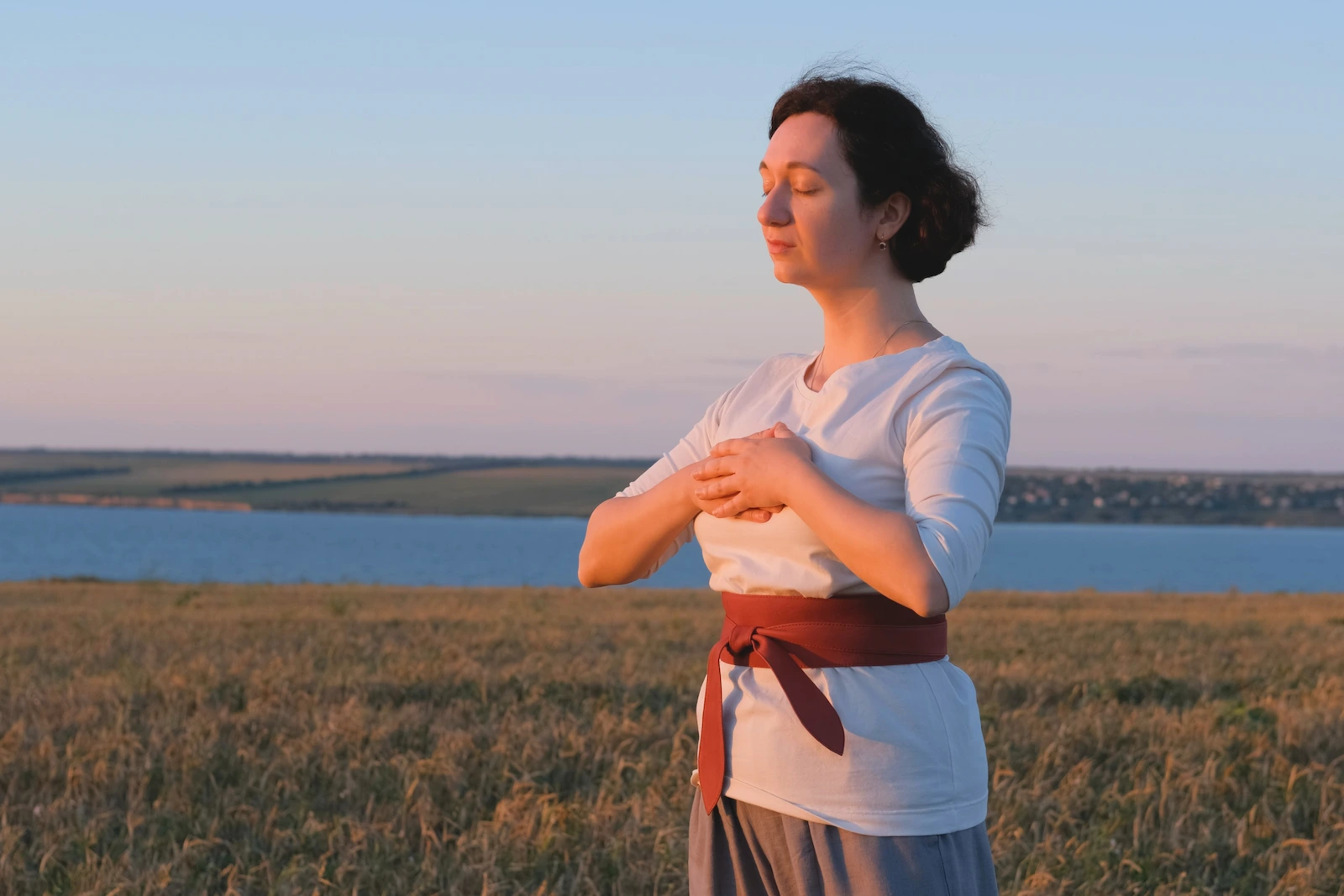 Une femme au bord d'un lac pratiquant le qi gong de la femme