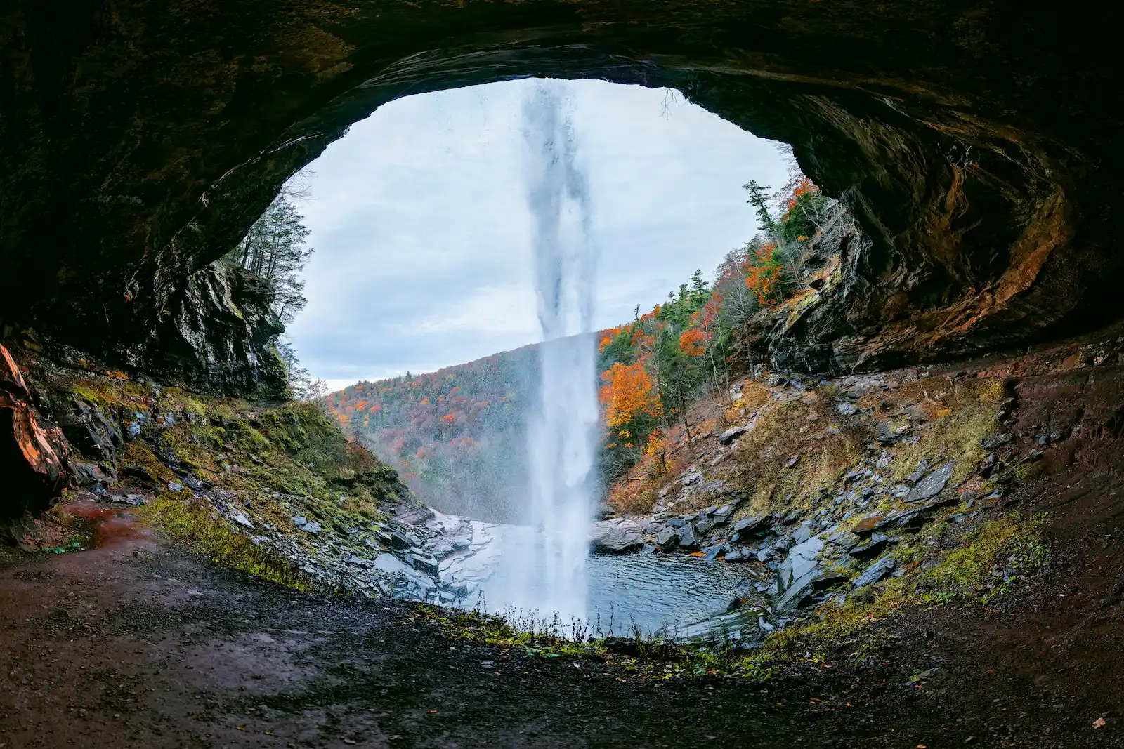Depuis l'entrée d'une grotte : paysage de montagne avec lac et cascade.