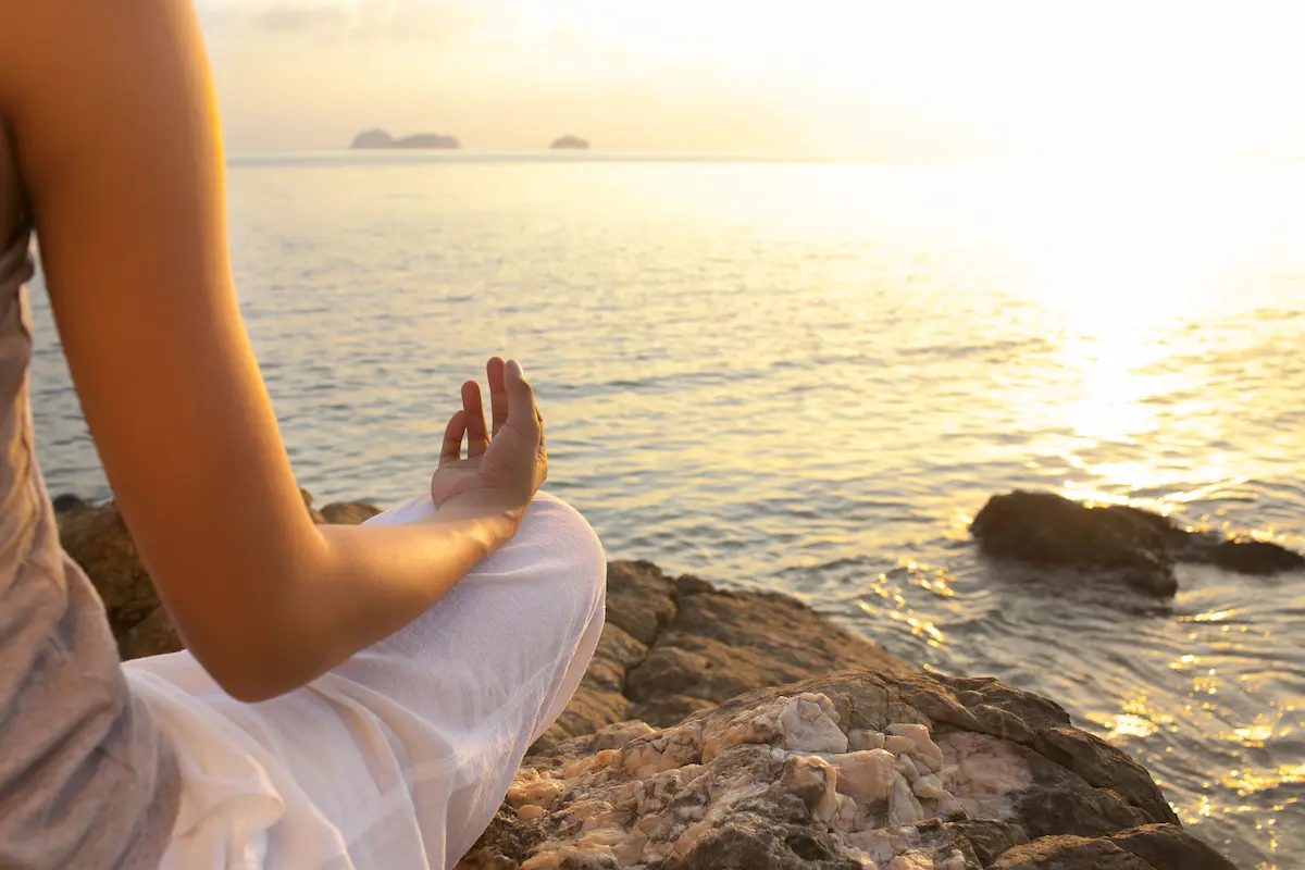 Une jeune femme assise en méditation face à la mer