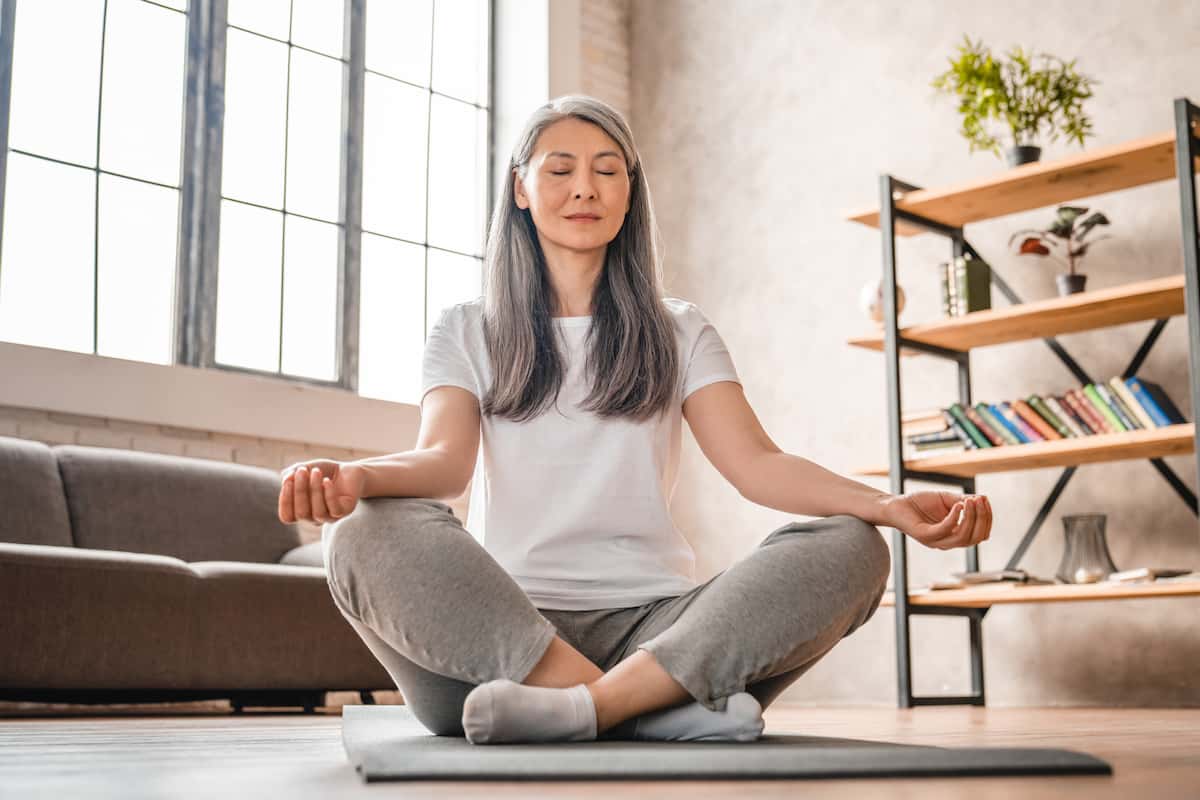 Femme assise en méditation dans son salon