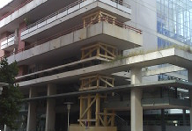 Bâtiment en béton avec des piliers renforcés par une structure temporaire en bois pour support.