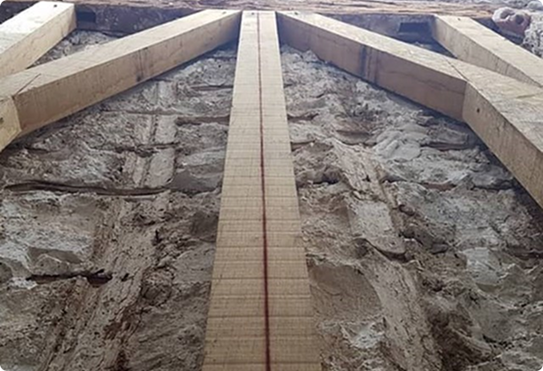 Vue en contre-plongée d'une structure en bois clair contre un mur en pierre rugueuse.