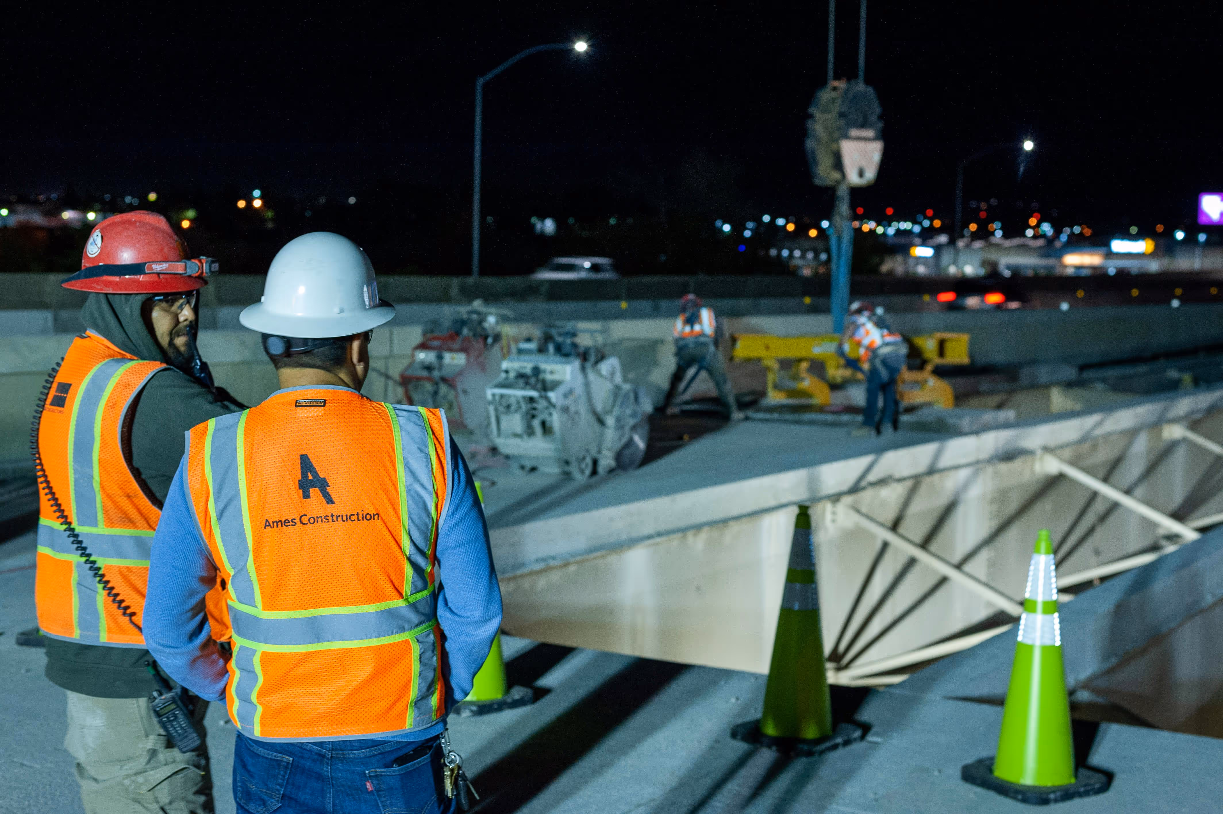 A site engineer and a construction worker looking down into a construction pit at night