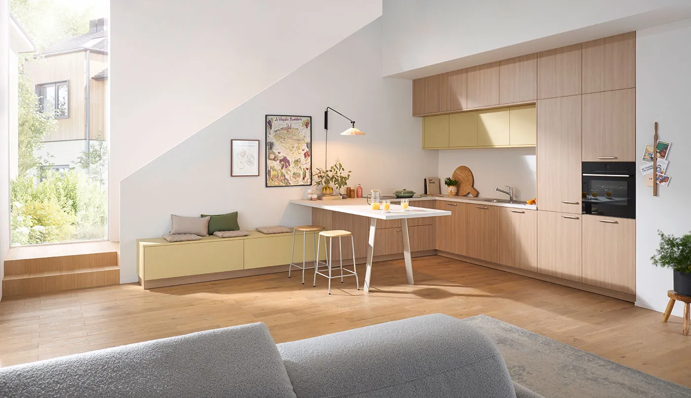 Helle, moderne Wohnküche mit Holzfronten, gelben Oberschränken und Sitzbank am Fenster.