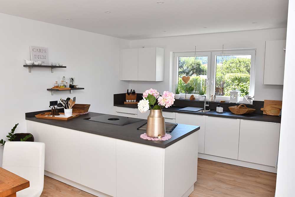 Helle weiße Küche mit dunklen Arbeitsplatten.
