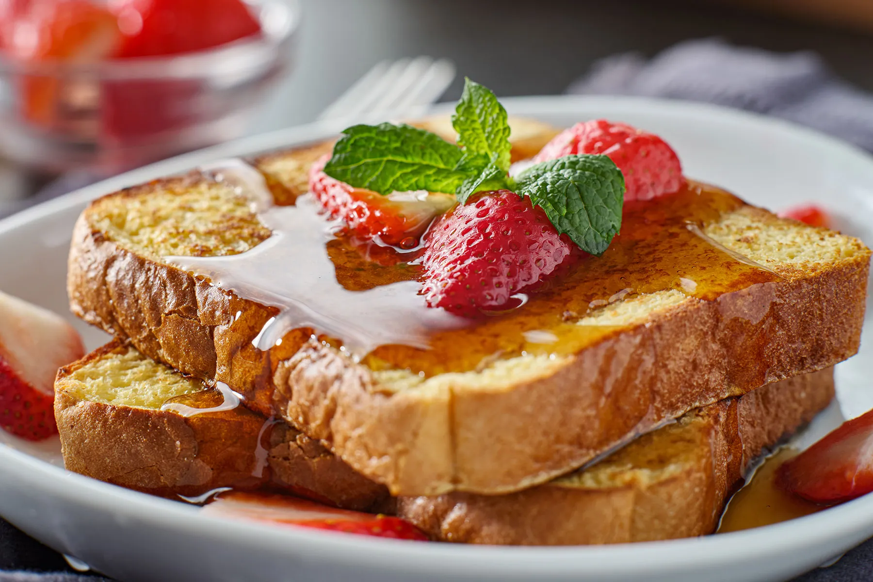 Zwei Scheiben Brot mit Honig und Erdbeeren drauf.