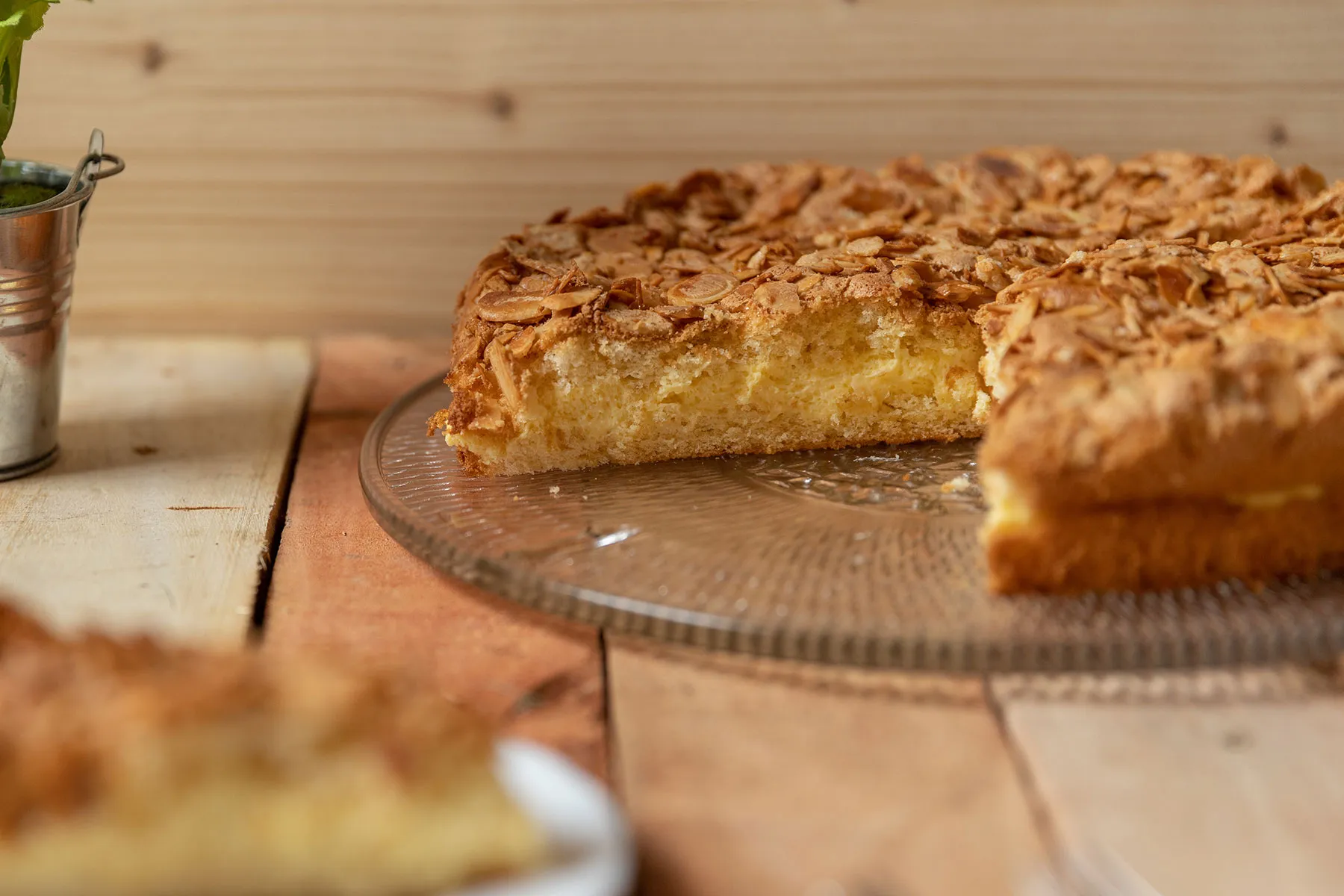 Ein Glastablett mit einem frisch geschnittenen Stück Bienenstichkuchen.