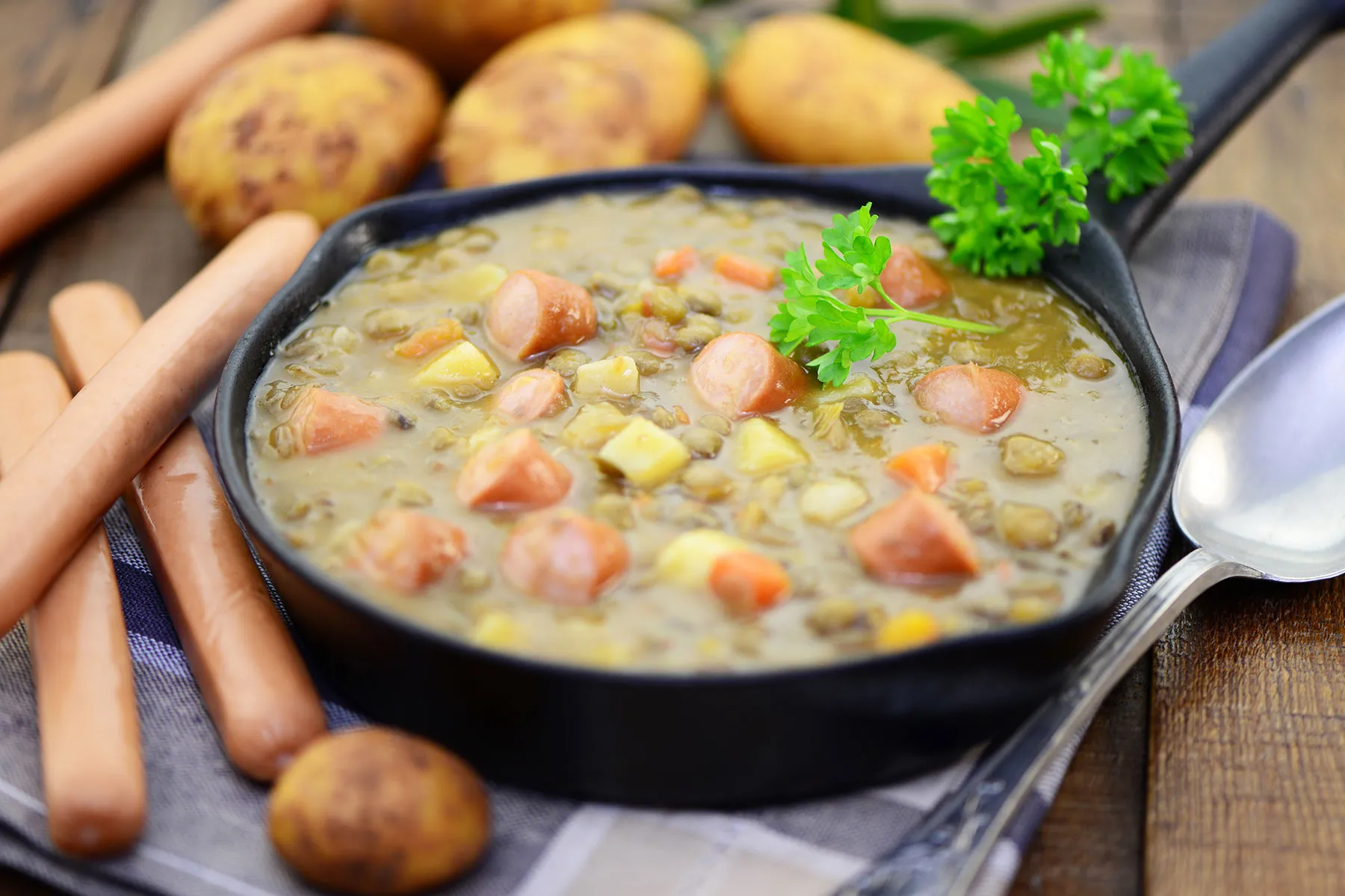 Eine Pfanne Suppe mit Kartoffeln, Gemüse und Würstchen.