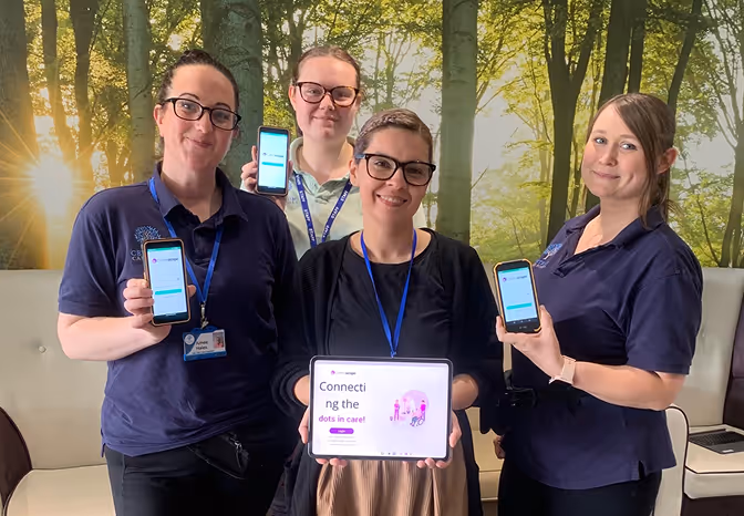 A group of people standing next to each other holding up cell phones.