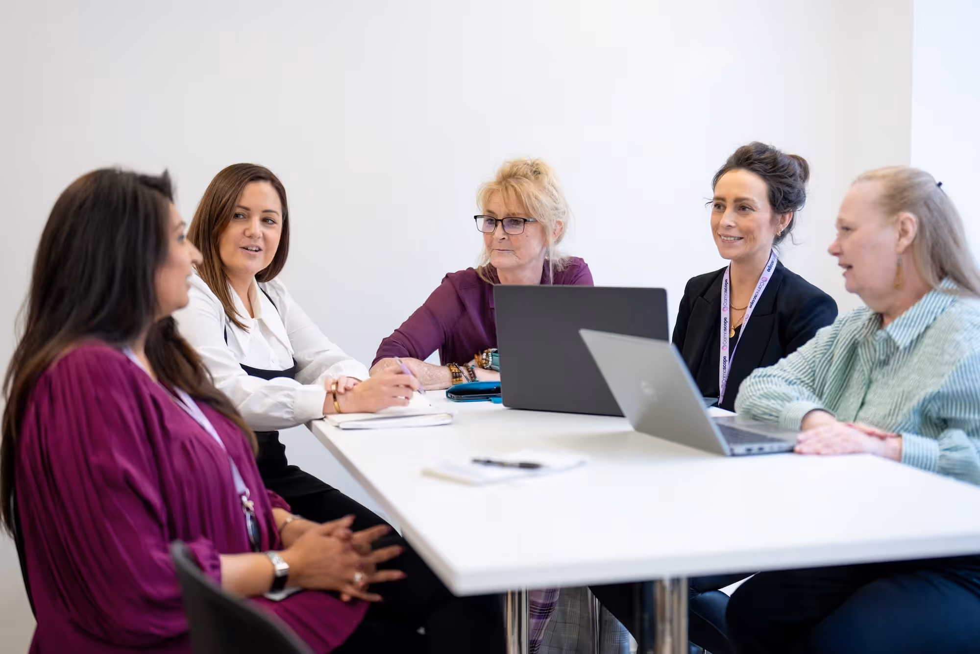 A group of women sitting around a white table.