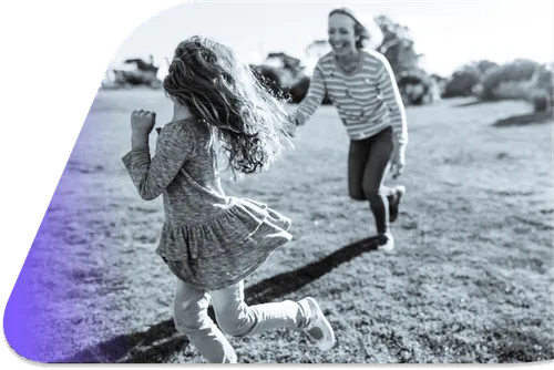A woman and a little girl running in a field.