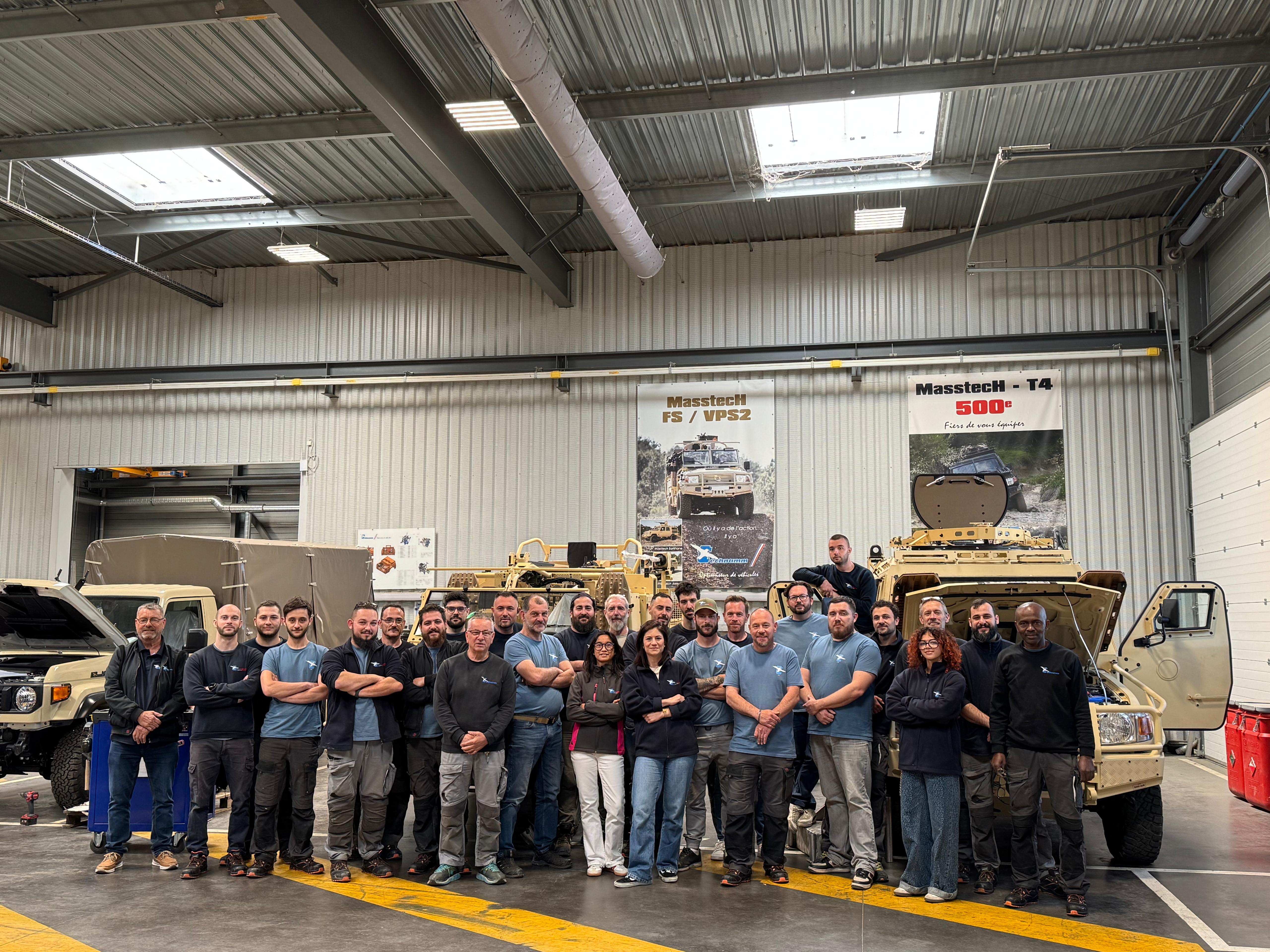 Technamm team posing in front of vehicles in the workshop.