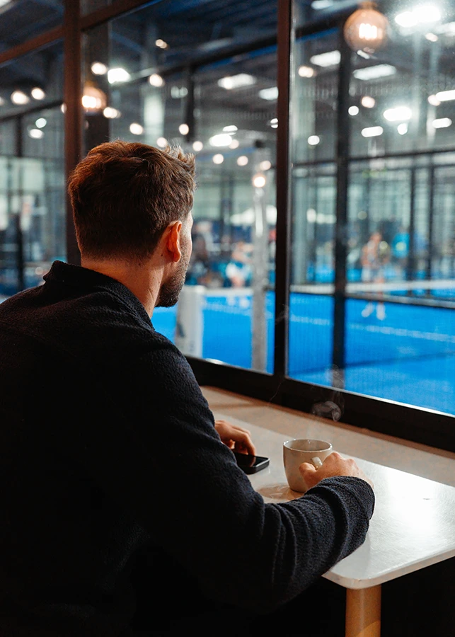 client de PadelShot en train de regarder une partie de padel depuis le club house