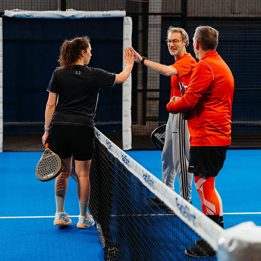 trois joueurs de padel au filet