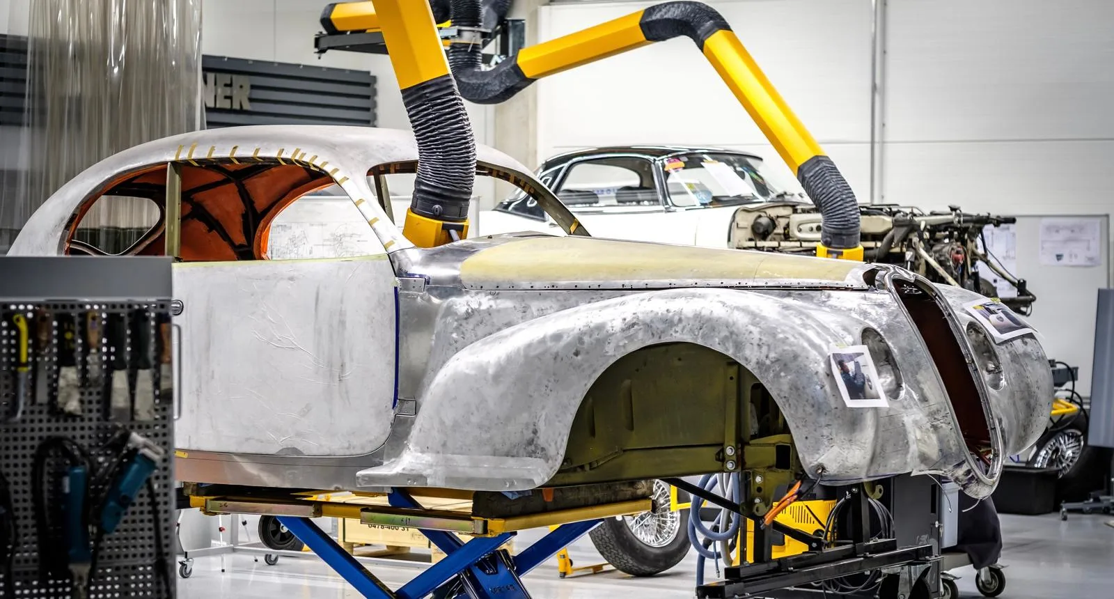 A Picture of an old Alfa-Romeo on a lift in a workshop