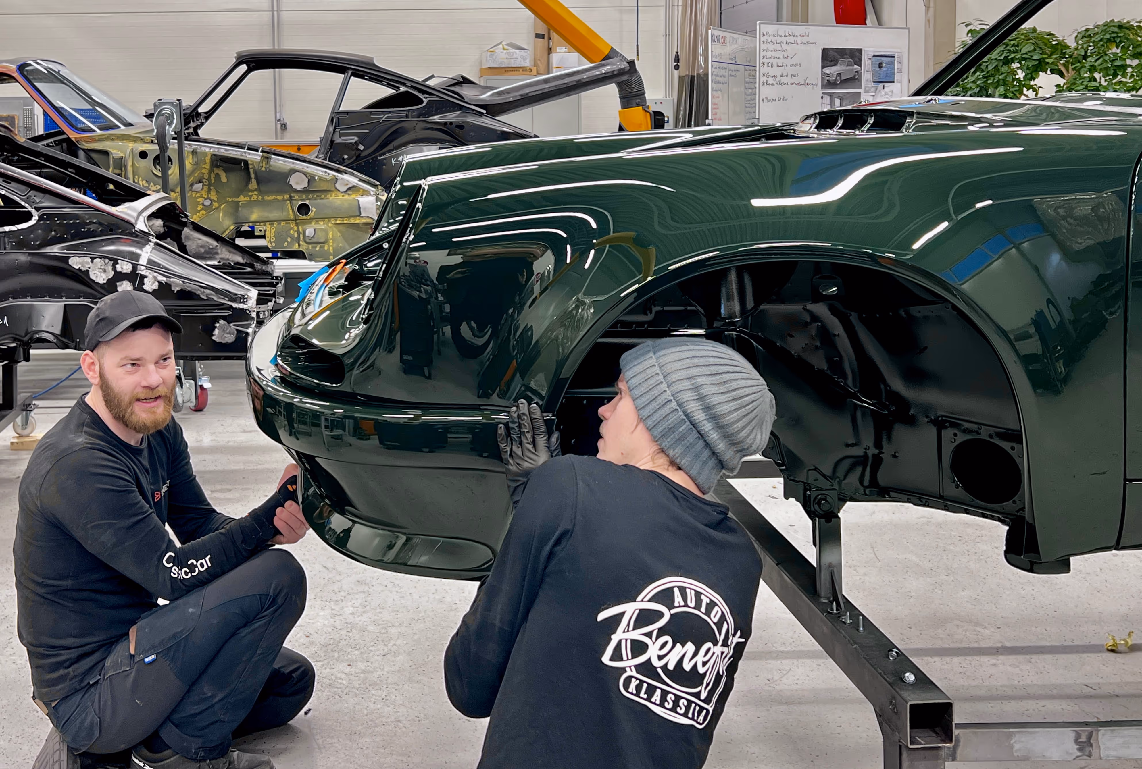 Green Porsche being worked on by two mechanics