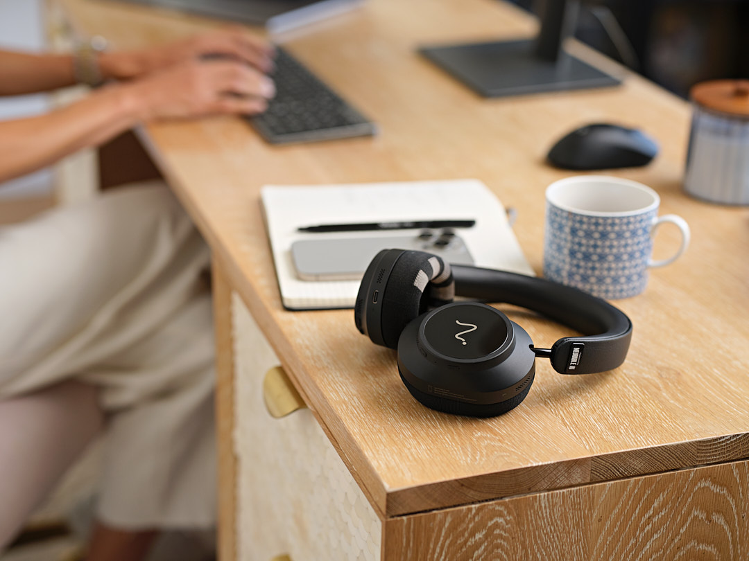 Neurable One headphones resting on a wooden desk beside a coffee mug