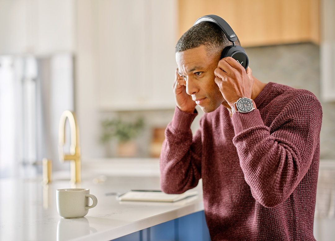 A man putting on Neurable One headphones at a kitchen counter