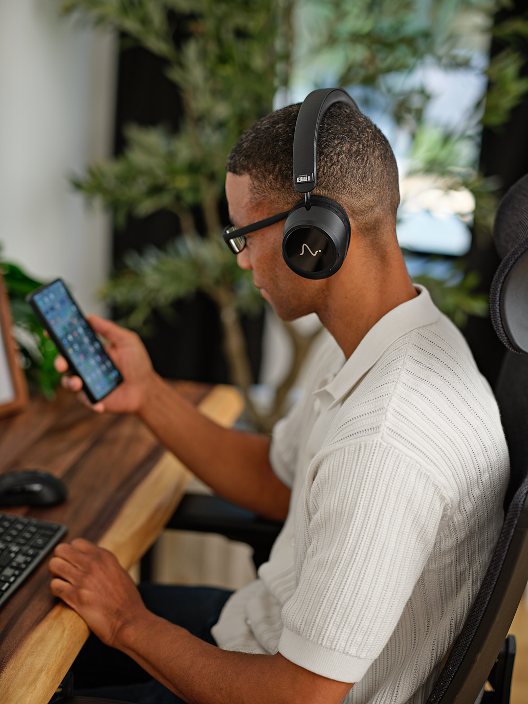 A man in glasses checks the Neurable One app on his phone at his desk