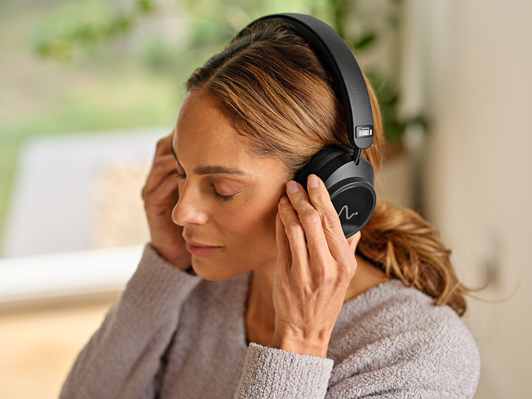 A woman with her eyes closed adjusting her Neurable One headphones