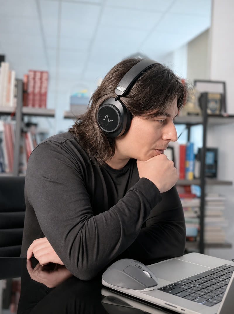 A man wearing Neurable One headphones while working at a laptop.