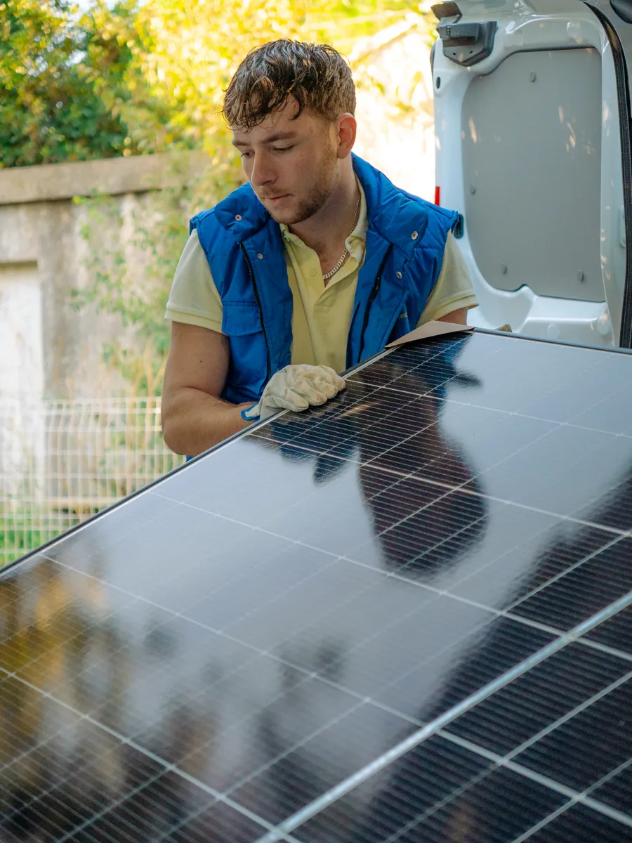 Technicien ADSolar portant un panneau solaire pendant une installation