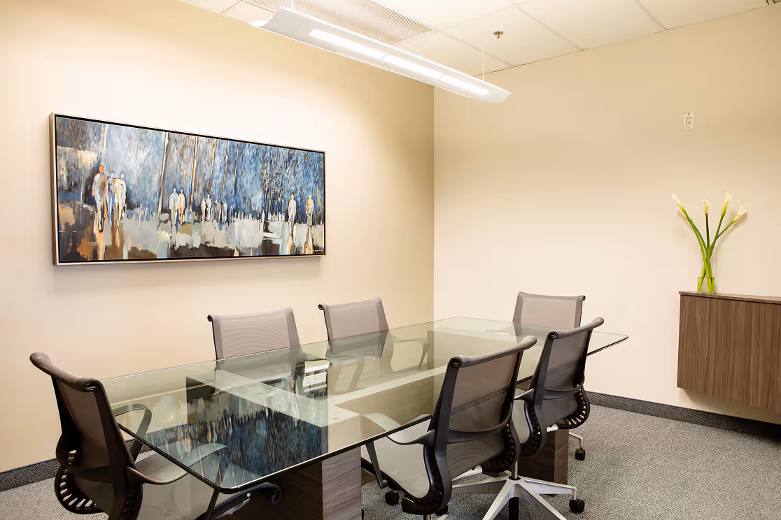 Chalati office meeting room with a glass desk, office chairs, and a painting on the wall.