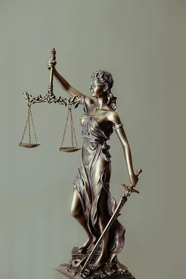 bronze statue of woman in blindfolds holding up scales in one hand and a sword in the other.