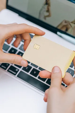 hands holding a card over a computer keyboard