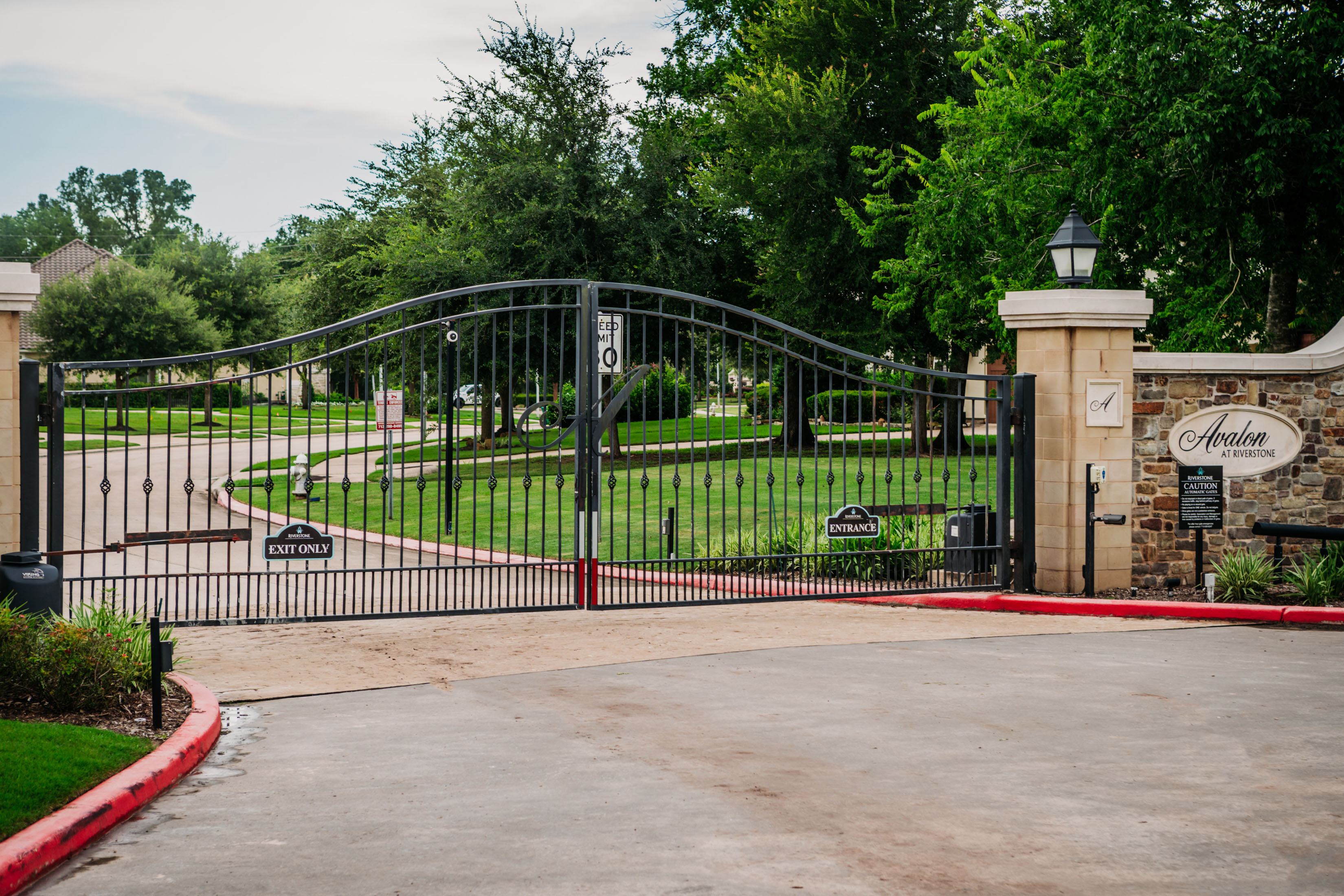 Iron Vehicular Entry Gate with Stone Masonry Columns offers Security and Gated Exclusivity