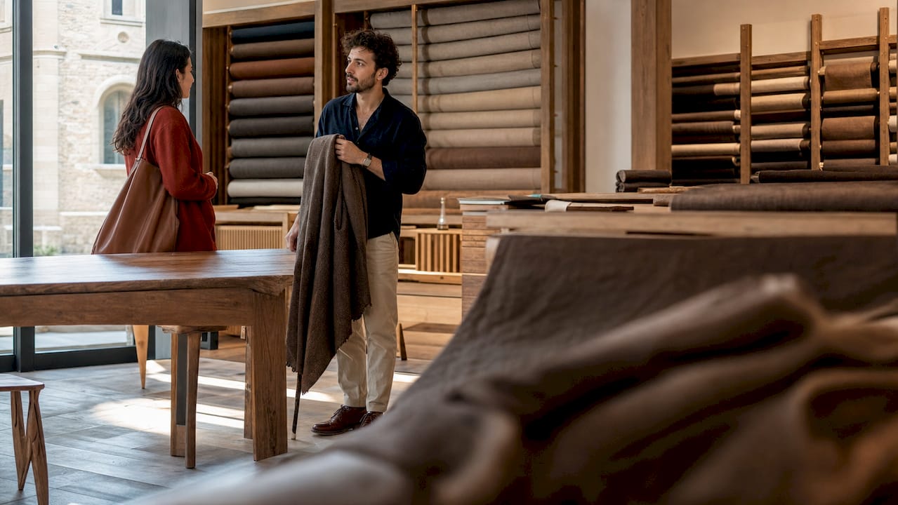 Designer assessing Italian linen fabric softness in showroom