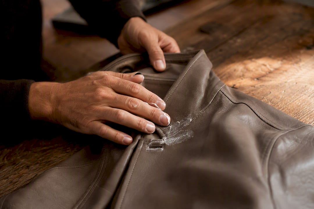Fingers applying conditioner on leather elbow patch