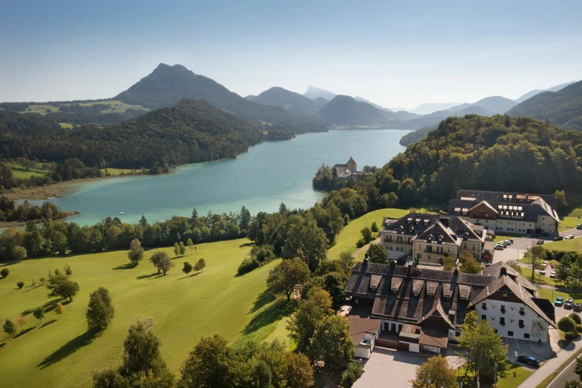 An aerial view of the grounds of the Arabella Jagdhof Resort am Fuschlsee with a lake in the distance
