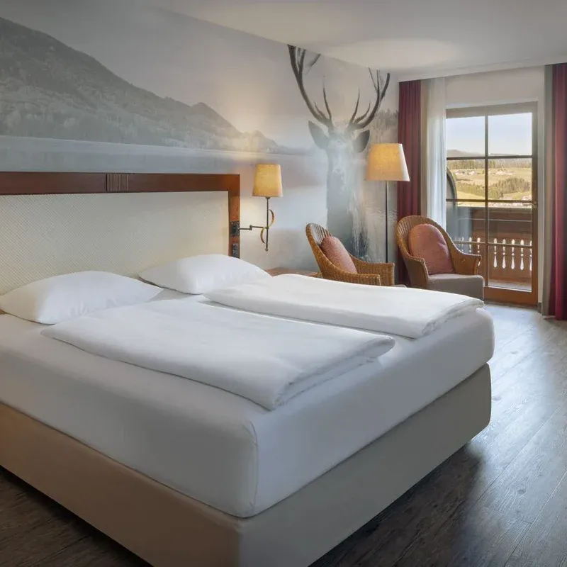 The Fuschl Nature guest room in the Arabella Jagdhof Resort am Fuschlsee showing a bed and two chairs